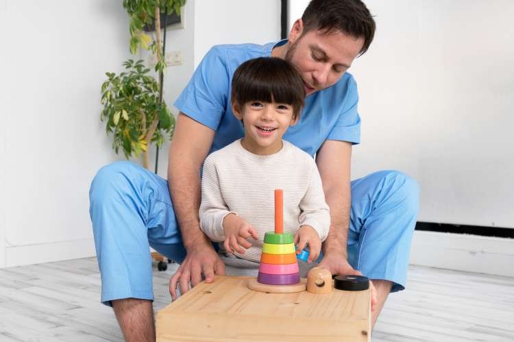 Photo young therapist helping cute little boy who has cerebral palsy playing with developing toy at rehab