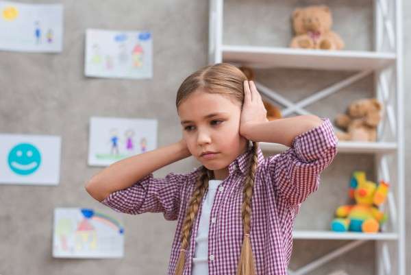 photo portrait of sad girl covering her ears with two hands